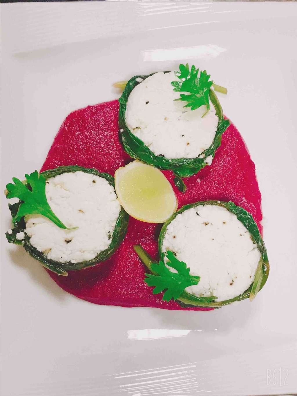 Cottage cheese stuff spinach roll, glazed in lemon and butter on beetroot makhni gray.